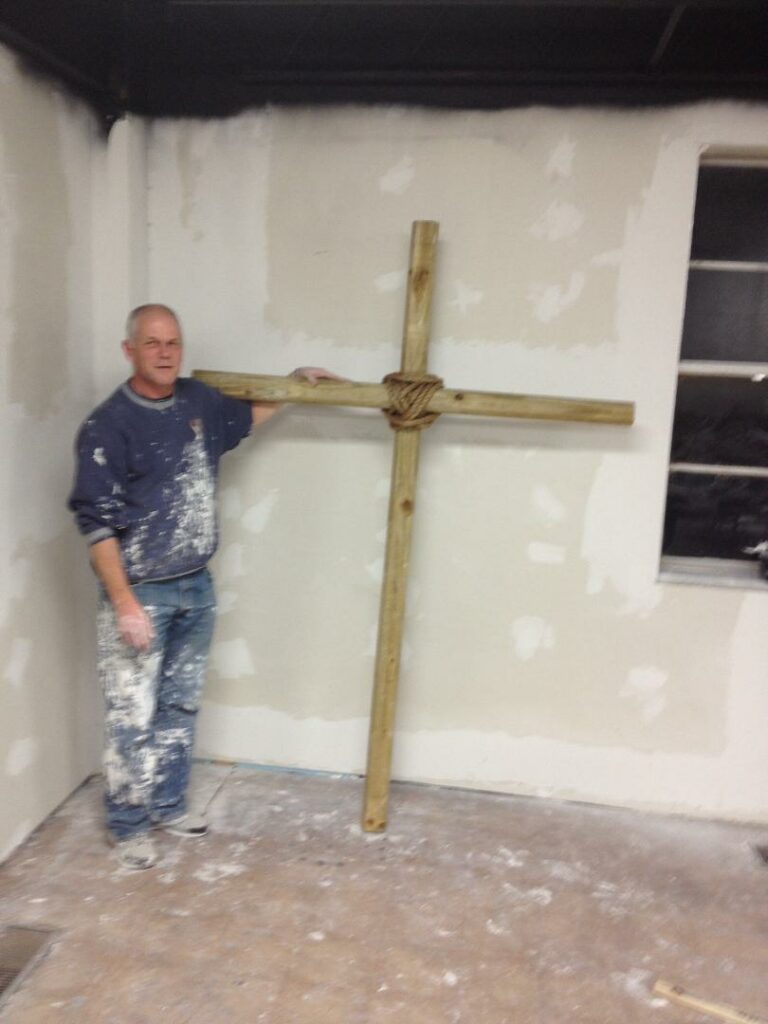 Randy holding a cross inside a house being remodeled